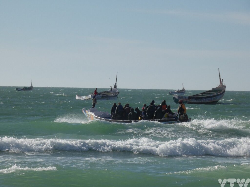 Sea at Nouakchott beach with colourful fishing boats going out fishing