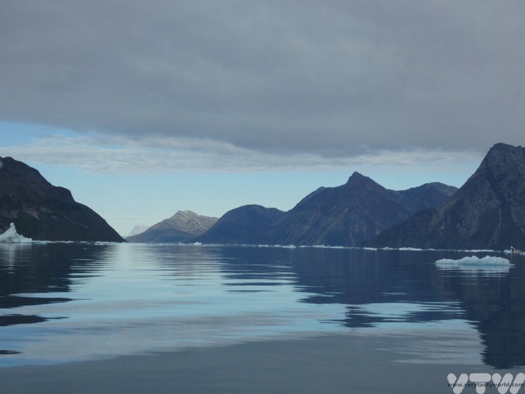 view of Nuuk fjord water with icebergs and surrounding mountains
